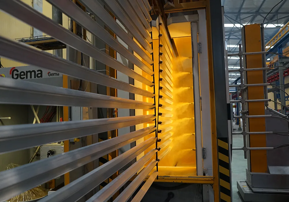 Pultruded FRP profiles entering a Gema powder coating oven on a factory production line