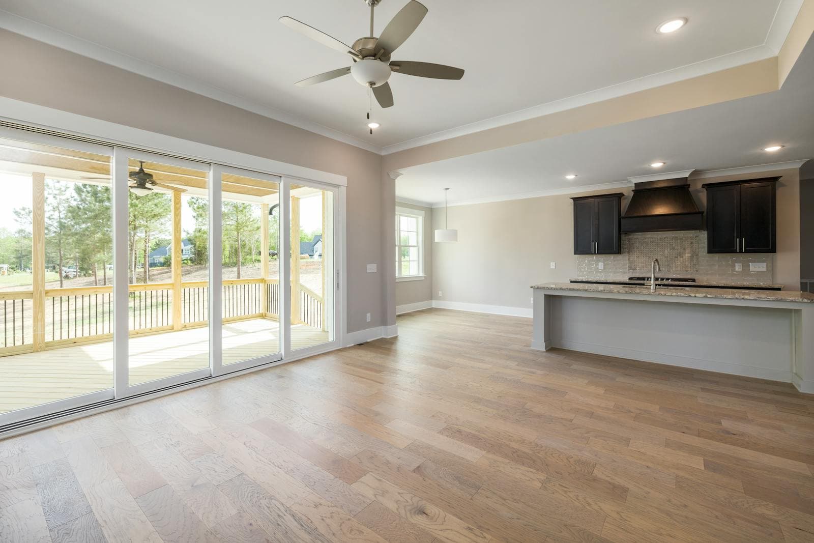 Bright open-plan residential interior with wooden flooring and large sliding glass doors opening onto a veranda — the form factor tested in this AS 2047 evaluation