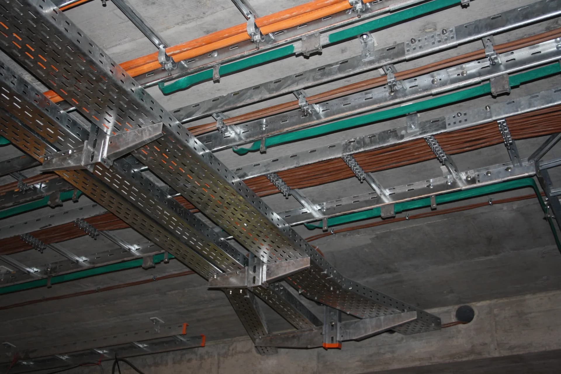 Metal cable ladders mounted beneath a ceiling above perforated cable trays; an independent construction example, not an FRP or F1 installation