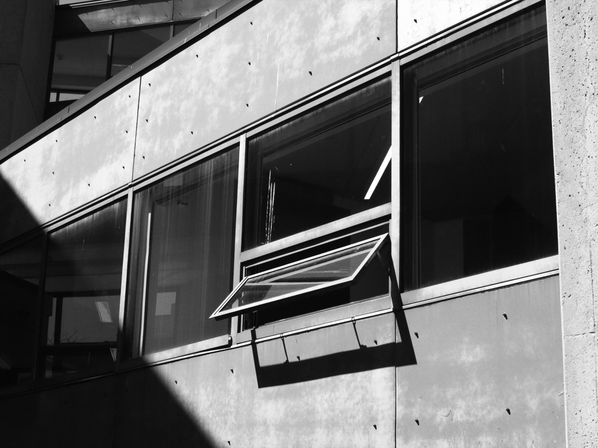 Modern facade with an opened awning window in black and white — supplier qualification is about what you verify before the windows are on the building