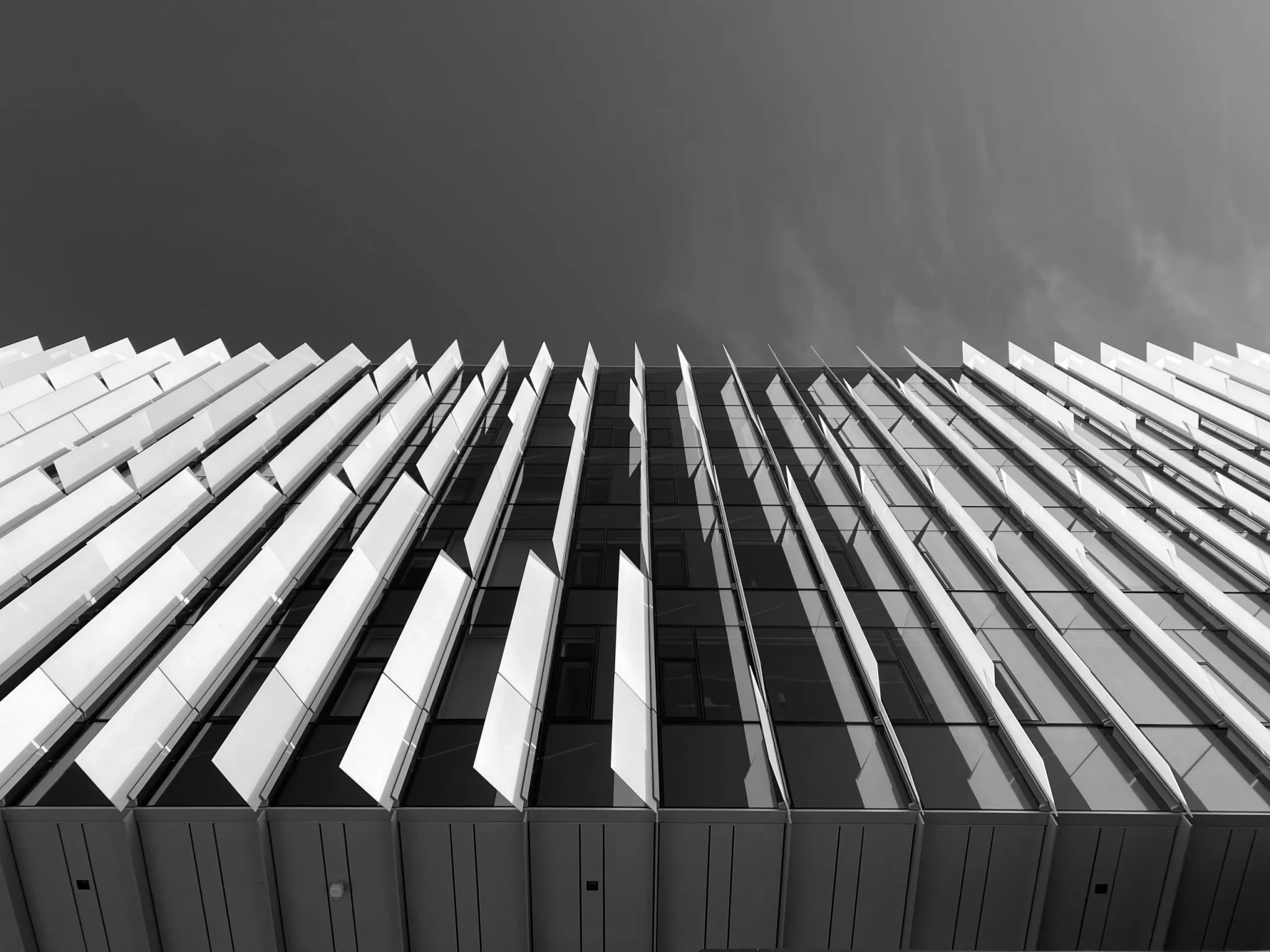 Angled louver blade sunshade facade — biaxial wind and gravity loads carried by the blade section