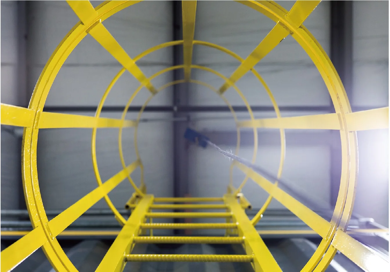 Fiberglass fixed ladder with a safety cage fixed to an industrial structure
