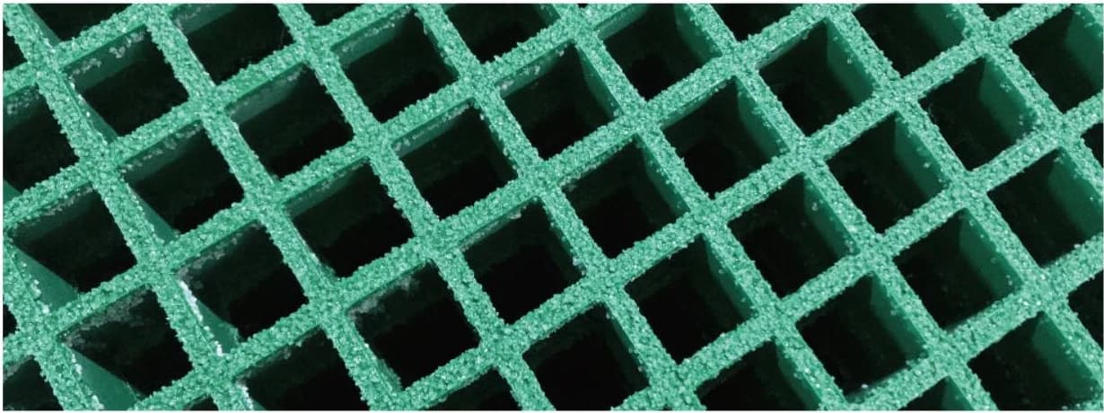 Close-up of green molded fiberglass grating with square mesh and a bonded grit walking surface