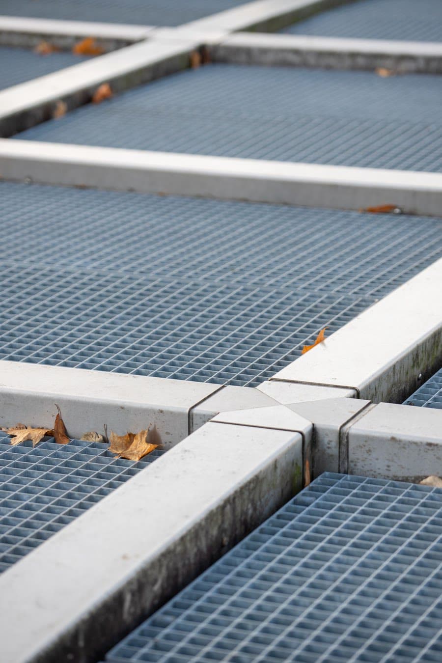 Close-up of molded FRP grating panels and load-bearing beams on an outdoor platform — slip-resistant mesh surface and corrosion-resistant vinyl ester construction