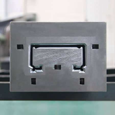 Front face of a steel pultrusion die showing the channel-shaped cavity and mounting openings