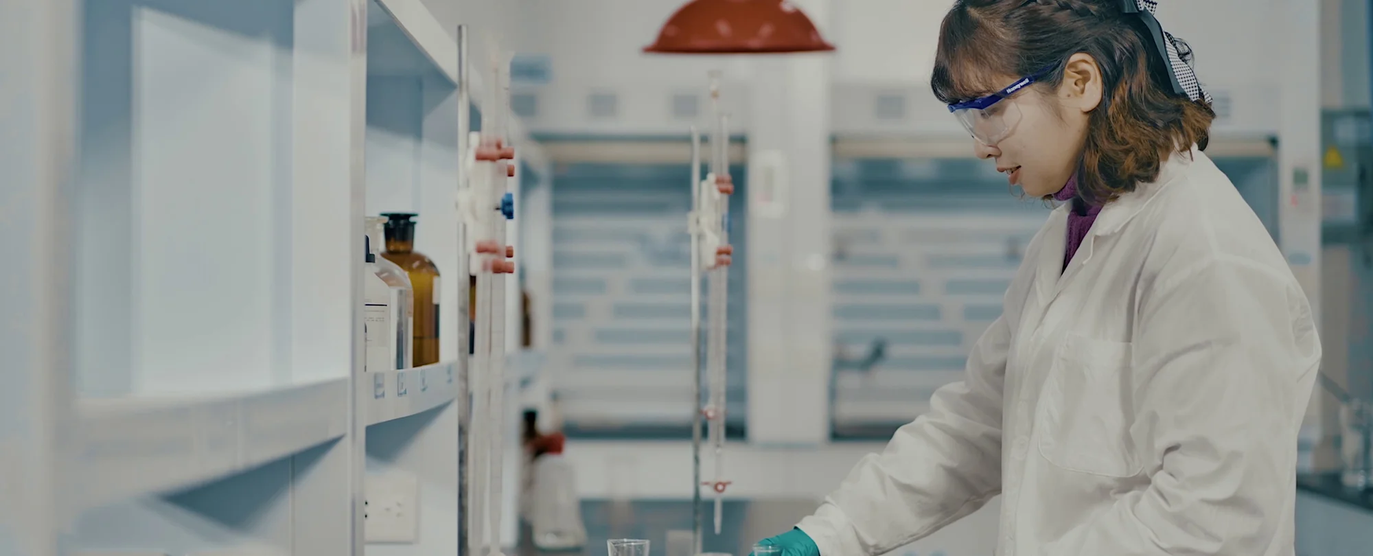 F1 Composite quality-testing chemist performing wet-chemistry titration on a pultruded composite sample in a controlled laboratory environment